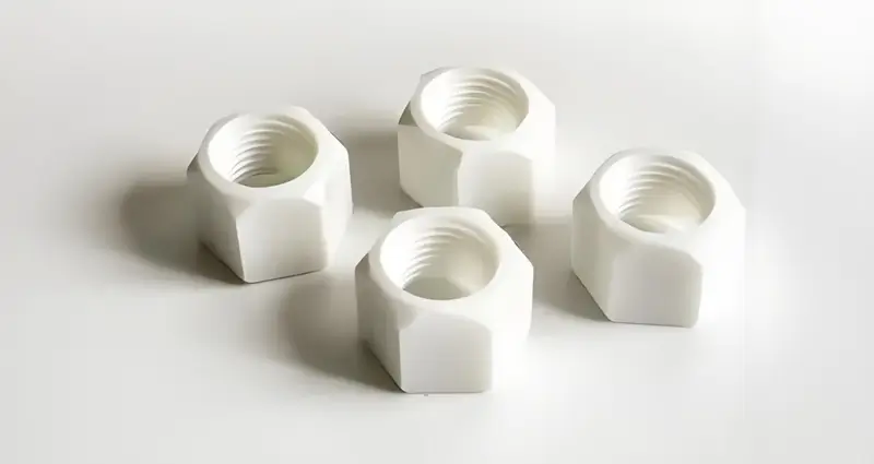 Injection Molded Threaded Products Four white hexagon nuts on a white background