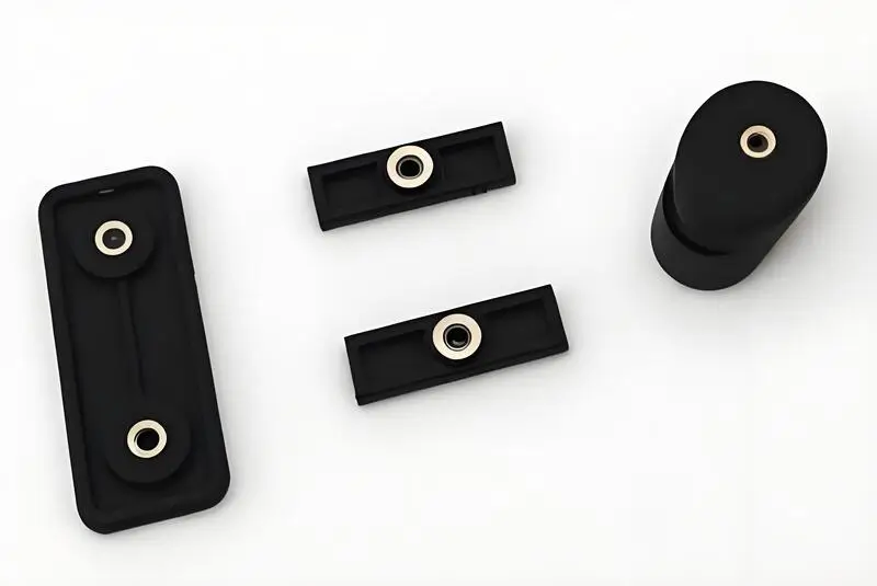 A set of black rectangular and cylindrical insert molded parts