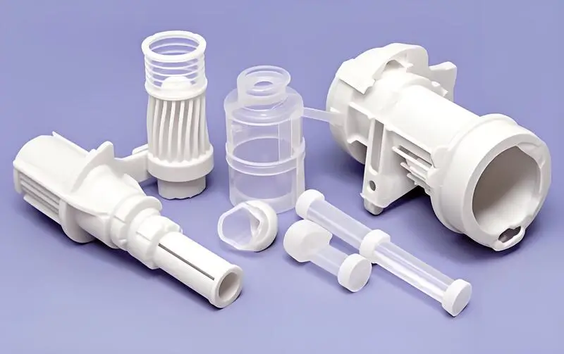 Assorted white injection molded plastic parts on a purple background