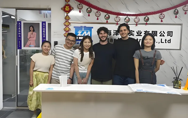 Six people standing together in front of a reception desk with a company sign in the background