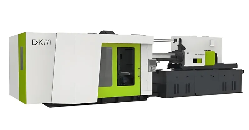 A large DKM injection molding machine with a white and green exterior